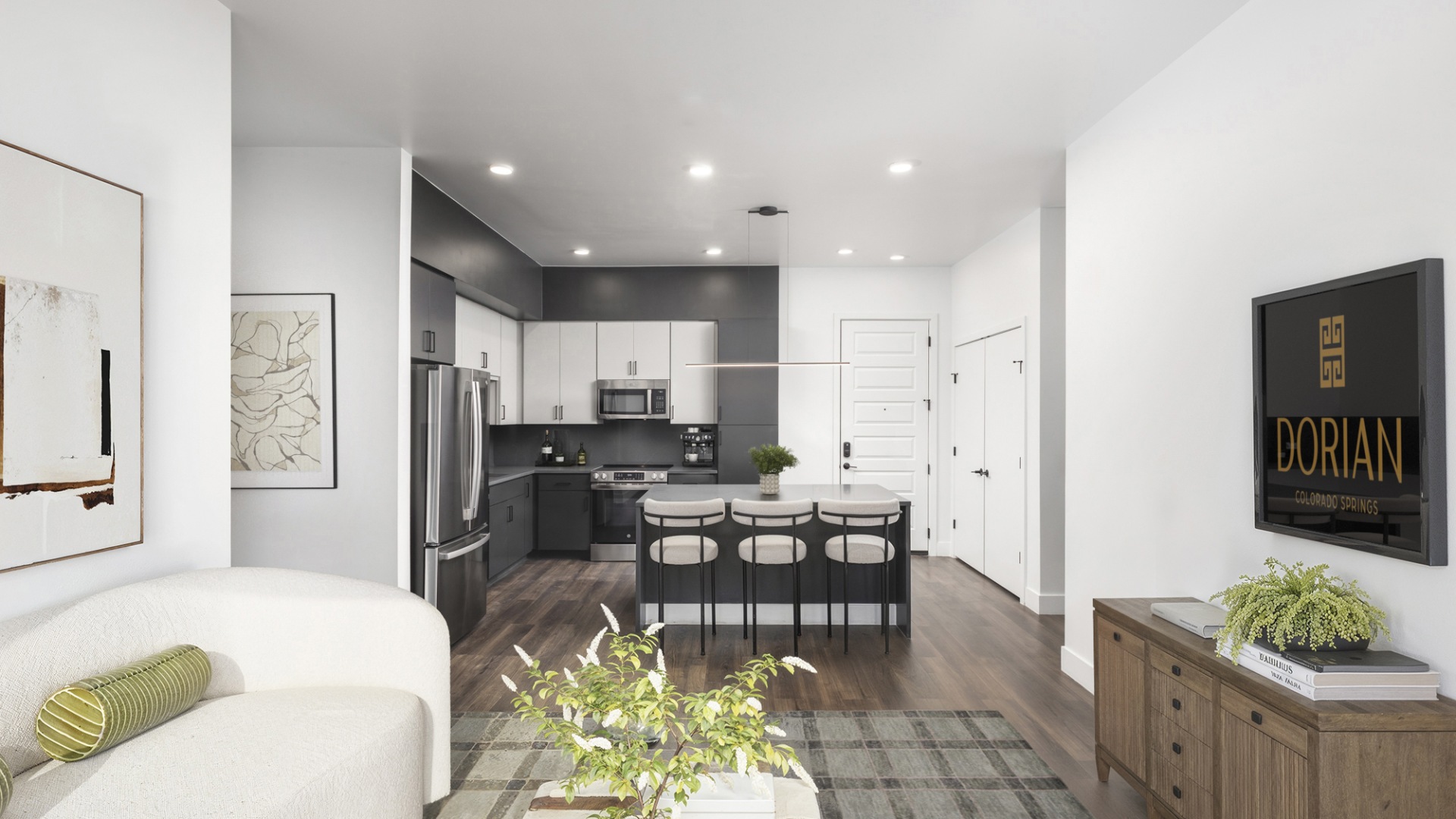 Modern open-concept living room and kitchen with sleek appliances, elegant decor, and inviting island seating in a luxurious apartment setting.	